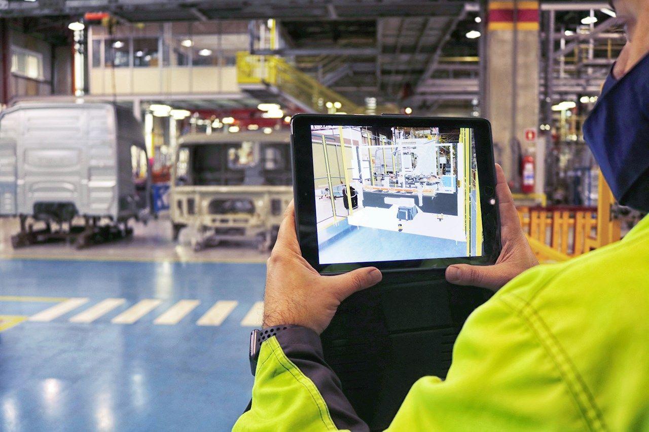 Delar av en person i en industrilokal som håller i en Ipad.