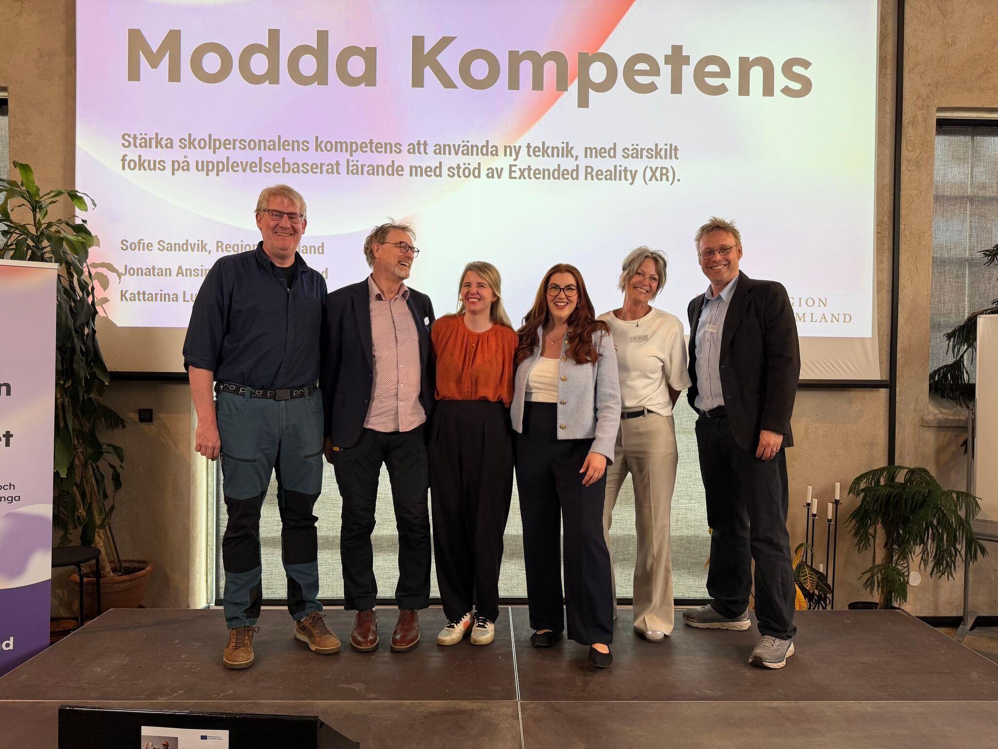 Personer på en scen med presentation i bakgrunden