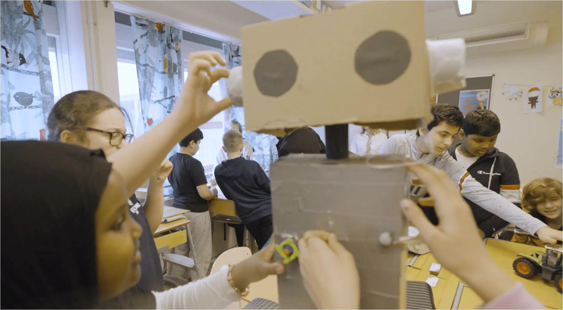 En klass som arbetar med en robotprototyp i kartong
