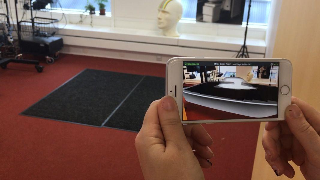 Bild på händer som håller en mobil och filmar ett XR laboratorium